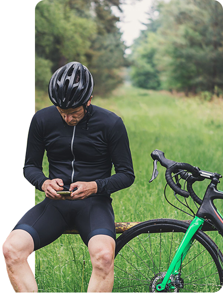 Imagem de um ciclista na natureza mexendo no celular